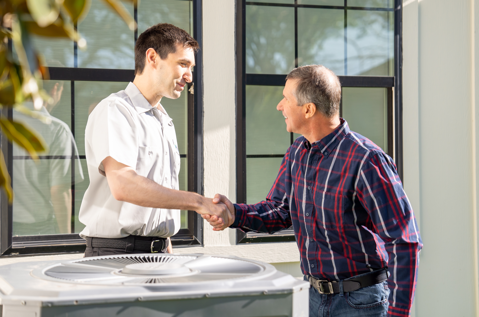 HVAC Technician and Phoenix homeowner standing near AC system